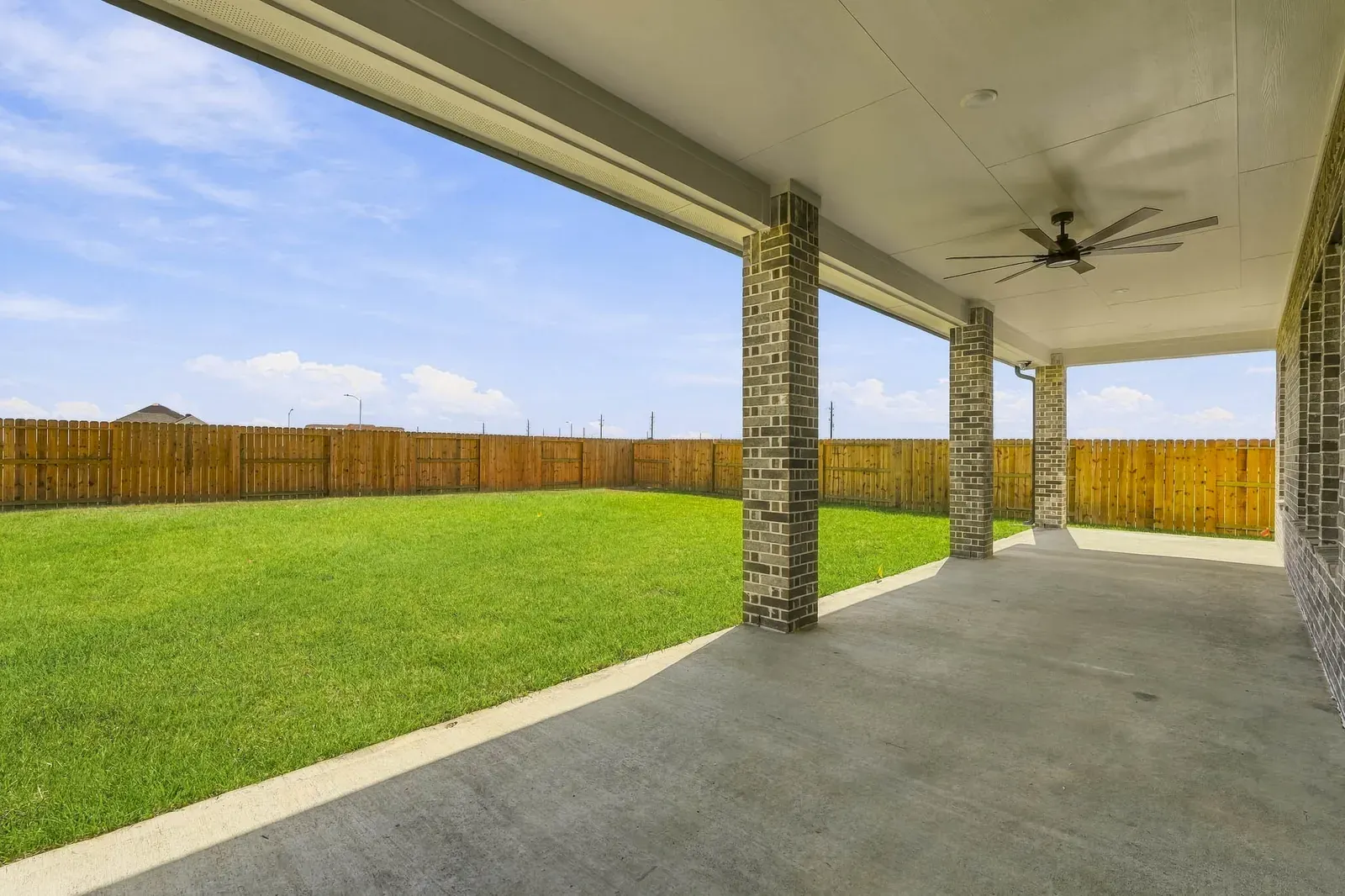 Covered patio with brick columns and a ceiling fan